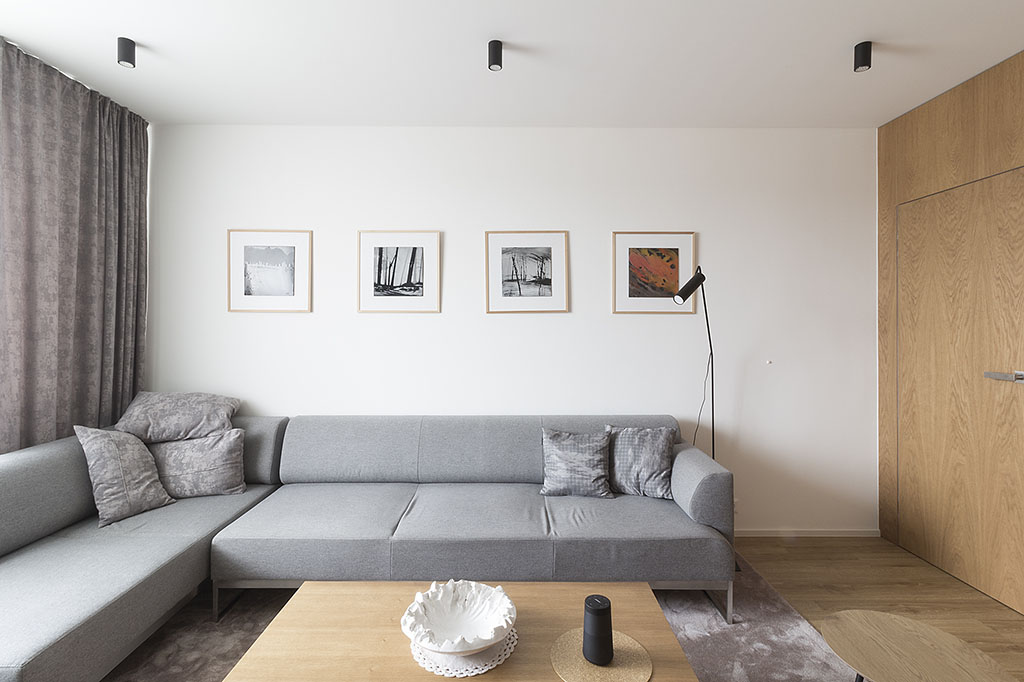 Bytová architektura obývacího pokoje s dubovou podlahou a stěnou doplněná o pohovku Noti.