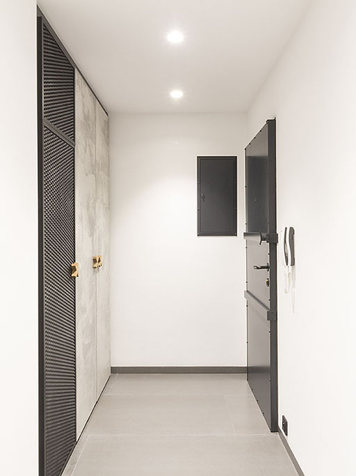 Design chodby s prvky interiéru v industriálním stylu a vestavnou skříní s dveřmi s betonovou stěrkou.