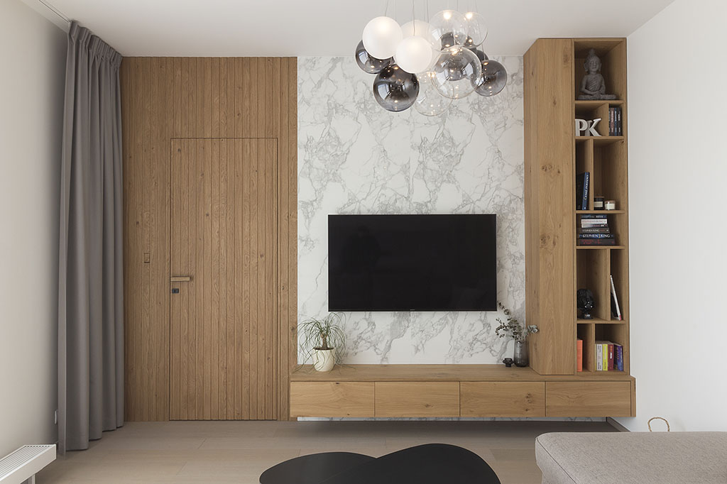 Design stěny v obývacím pokoji v kombinaci obkladu s mramorovým desénem a přírodního dubu.
