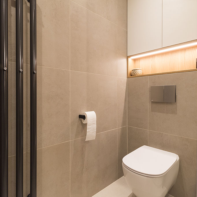 Návrh interiéru toalety s osvětlenou skříní s nikou nad WC v kombinaci dubu a bílého lamina.