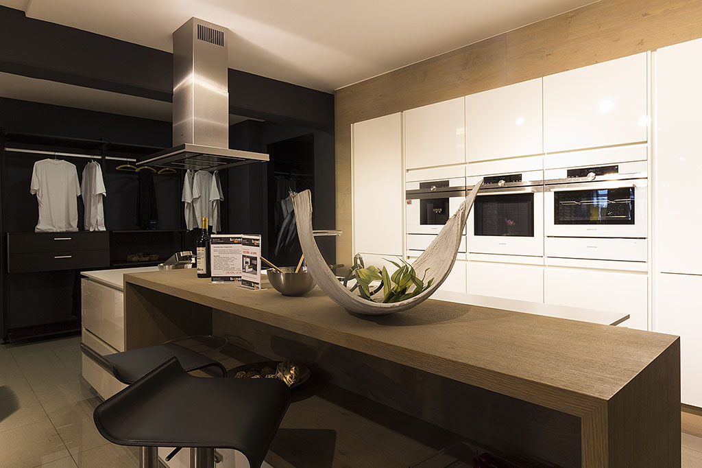 Design moderní kuchyně s ostrůvkem v prodejně Beneš nábytek v kombinaci bílé barvy a dubové dýhy v barvě tmavého dubu.