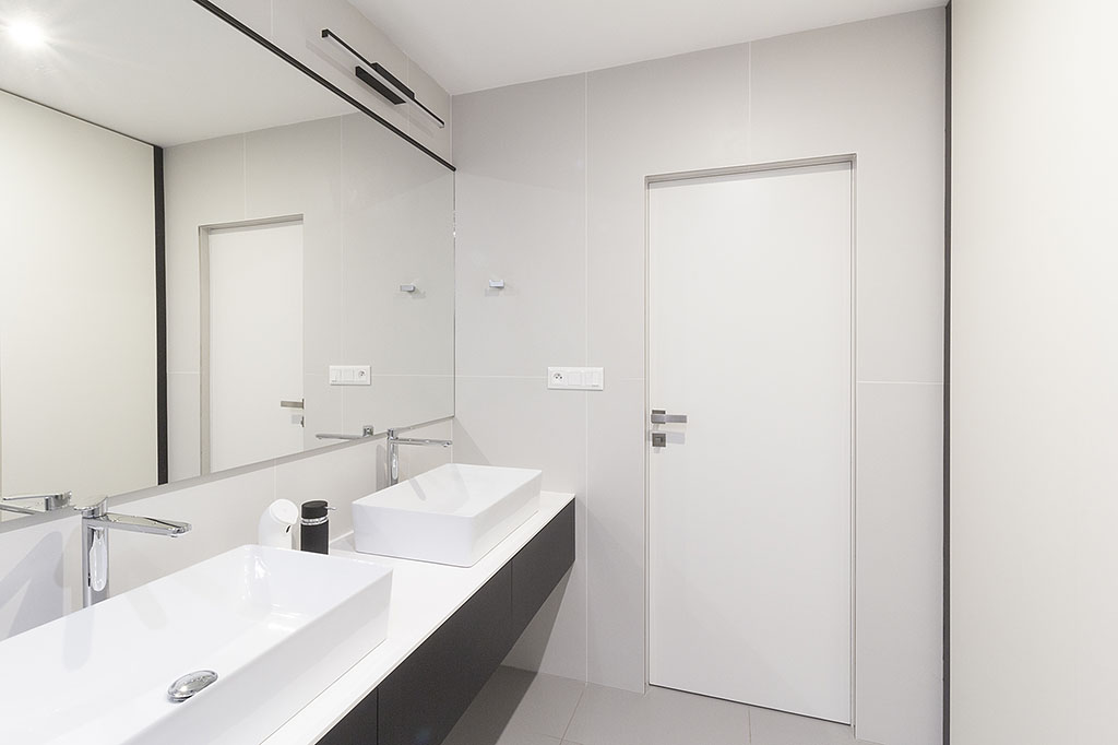 Návrh moderní koupelny v bíločerném provedení s umyvadly na desce a velkým obdélníkovým zrcadlem.