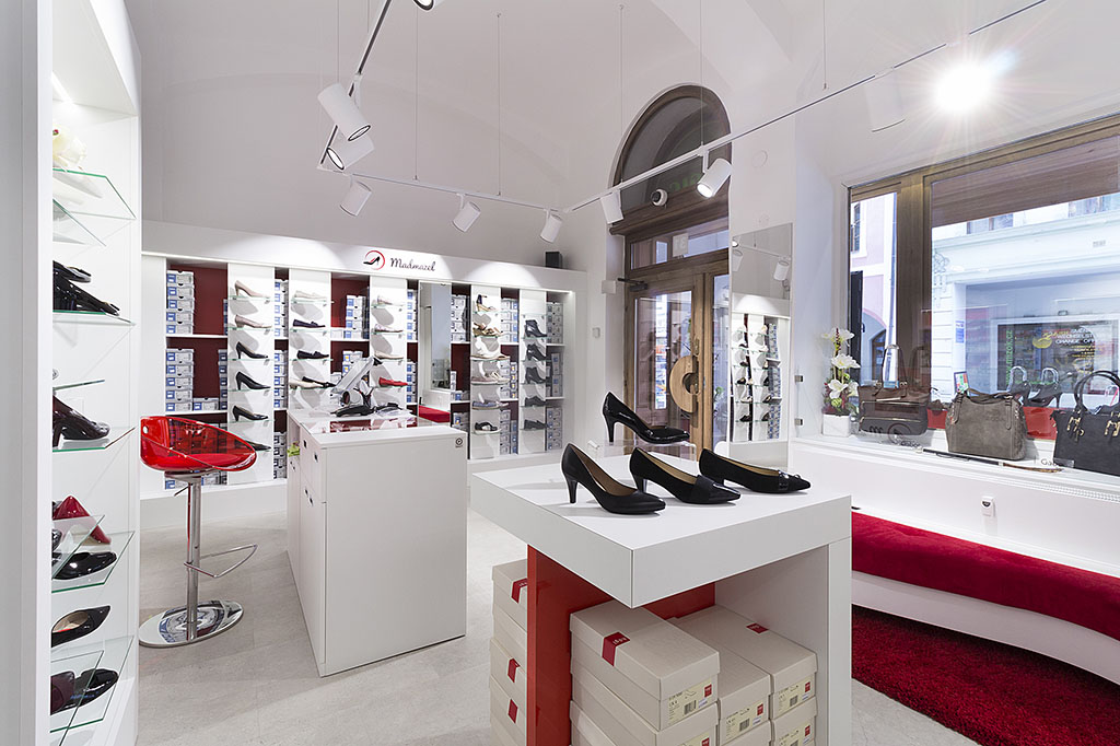 Návrh interiéru obchodu s obuví v kombinaci bílé a červené barvy. Design komerčních prostor.
