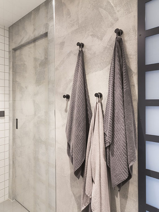 Design koupelny se stěnou s posuvnými dveřmi a betonovou stěrkou v šedé barvě.