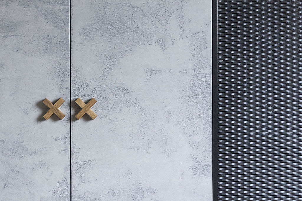 Design vestavné skříně s dveřmi s betonovou stěrkou a perforovanými dveřmi s výplní z tahokovu.