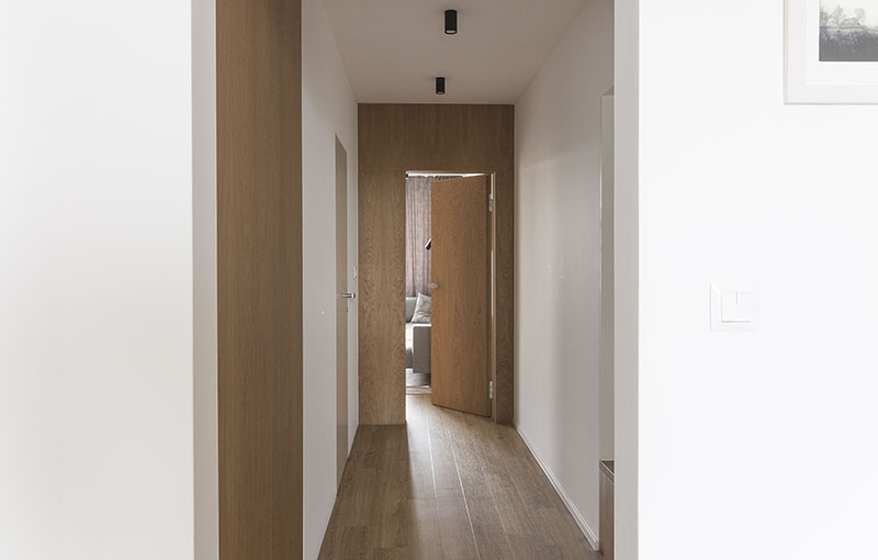 Design chodby s dveřmi se skrytou zárubní a dubovým obkladem stěny.